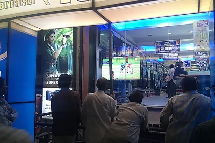 People watching an IPL match through a shop window